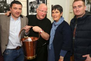 Christy Moore collects his replacement bucket with (LtoR) Mick Mooney, TMAP; Ronnie Fay, PP and John Sullivan, Traveller Visibility Group, Cork. ©Photo by Derek Speirs 